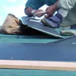 府中市　屋根が二重になる屋根カバー工法　コロニアル屋根の上に被せる横暖ルーフきわみを屋根の上で加工調整する施工スタッフ