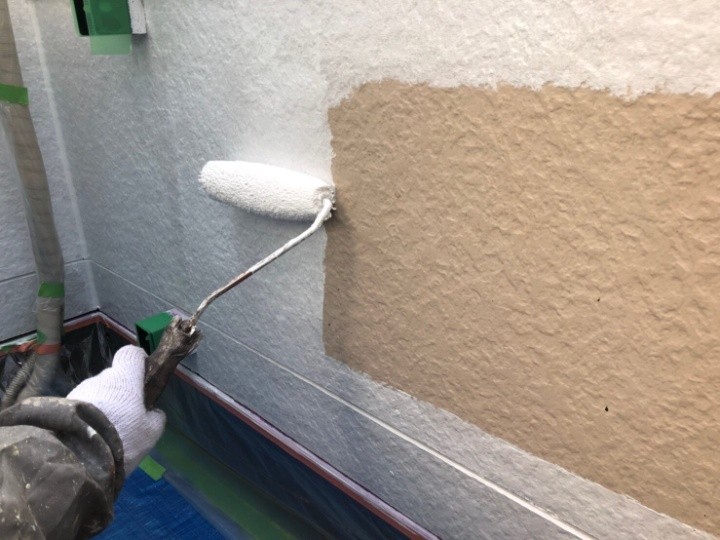 外壁に「中塗り・上塗り」作業する風景