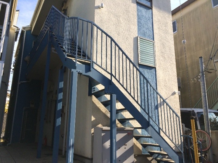 表面の青い塗料に色褪せが見られる鉄骨階段の手摺り