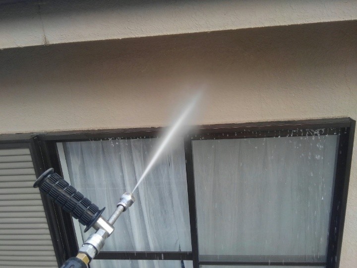 外壁に高圧洗浄する作業風景